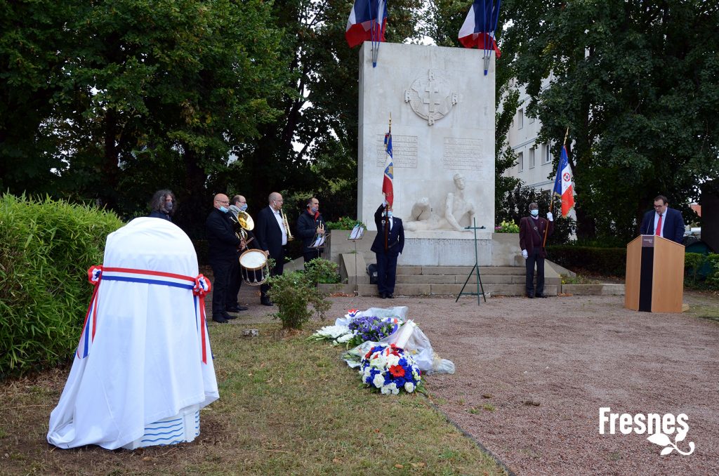 6 personnes avec fanfare, drapeau français, fleurs devant une grande pierre commémorative, une autre personne derrière un pupitre - Agrandir l'image, fenêtre modale