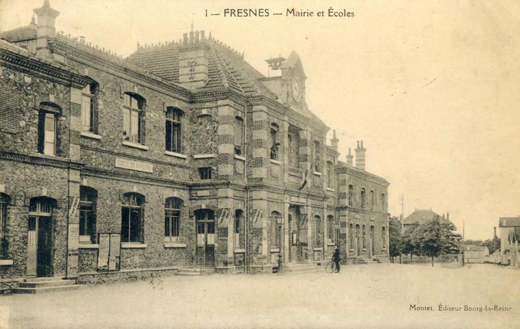 Carte postale en noir et blanc intitulée "1 - Fresnes - Mairie et écoles" en haut, et "Montet - Éditeur Bourg-la-Reine" en bas, montrant un solide bâtiment en pierre sur 2 étages dont l'entrée est largement en avant par rapport au reste du bâtiment, et surmontée d'une grosse horloge ; face à lui une place vide - Agrandir l'image, fenêtre modale