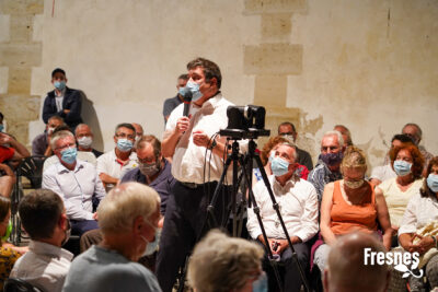 toujours dans cette même grande pièce, un autre orateur parle au micro, le public autour l'écoute - Agrandir l'image 7 sur 9, fenêtre modale