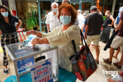 une femme dépose un bulletin de vote dans un urne inscrite "Régie publique de l'eau" - Agrandir l'image 8 sur 9, fenêtre modale