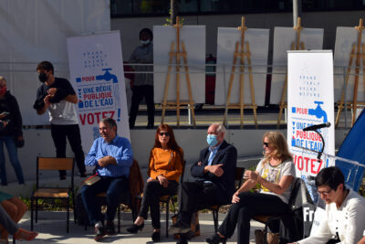 5 personnes assises sur des chaises face à d'autres personnes, des kakemono et des chevalets portant des panneau informatifs sont placés derrière eux - Agrandir l'image 2 sur 9, fenêtre modale